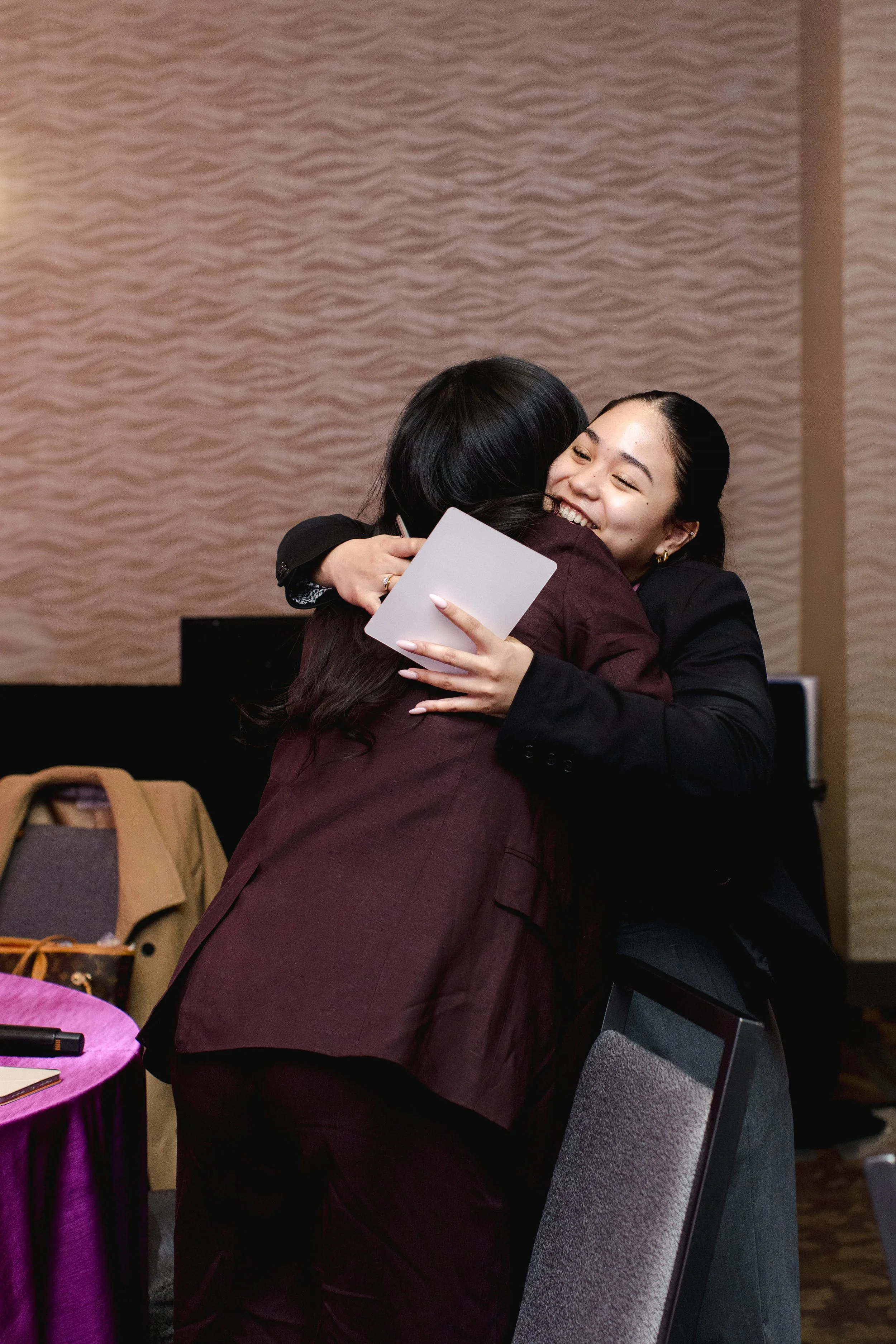Two attendees sharing a hug at Her Greatway.