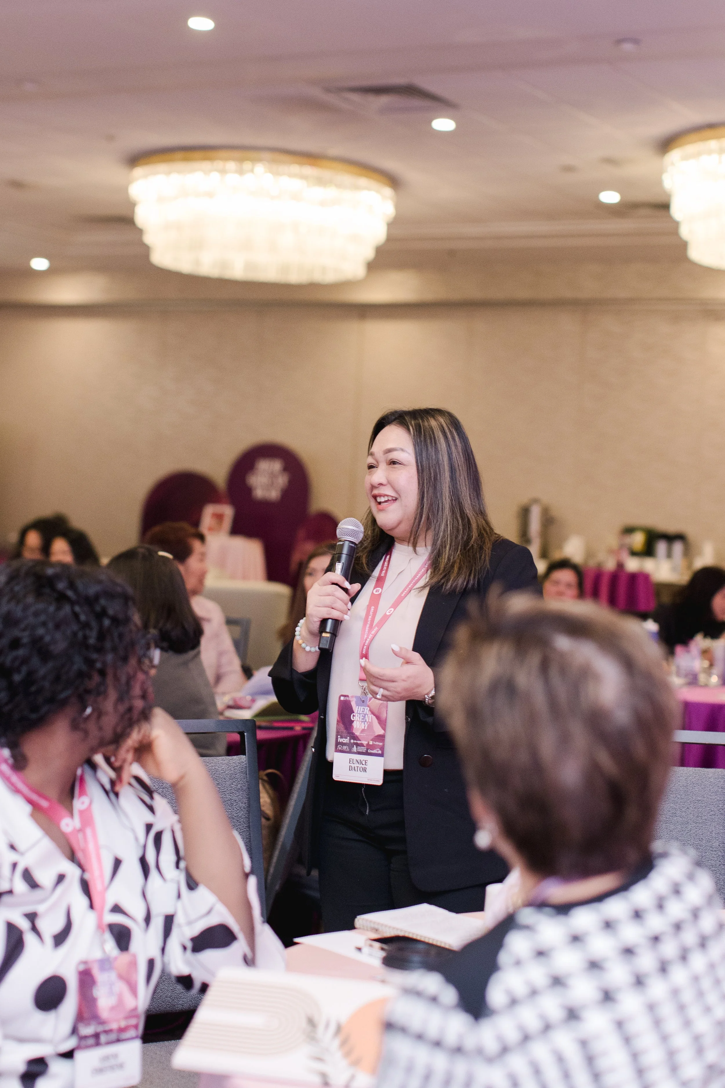Eunice Dator speaking with a microphone in front of attendees.