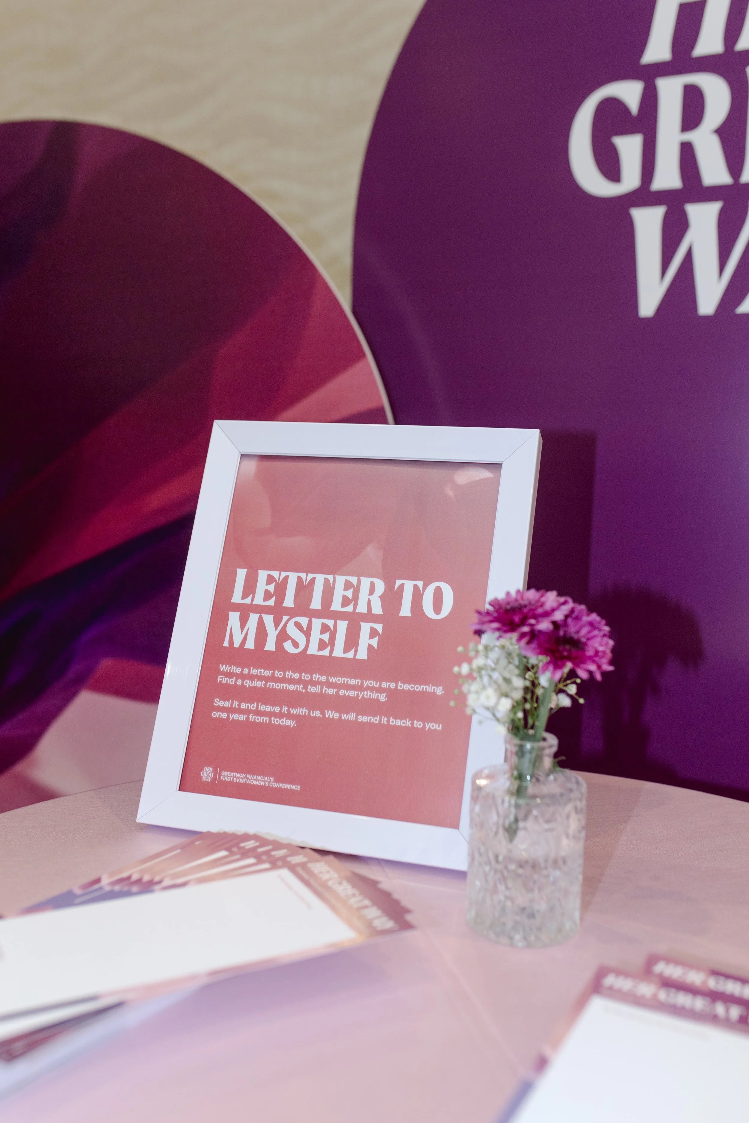 A framed sign reading Letter to Myself, beside a small vase of flowers.