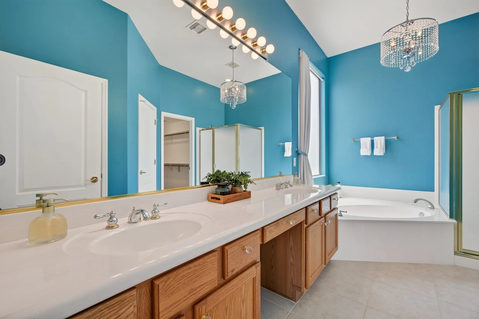 Primary bathroom with double vanity, soaking tub and chandelier lighting