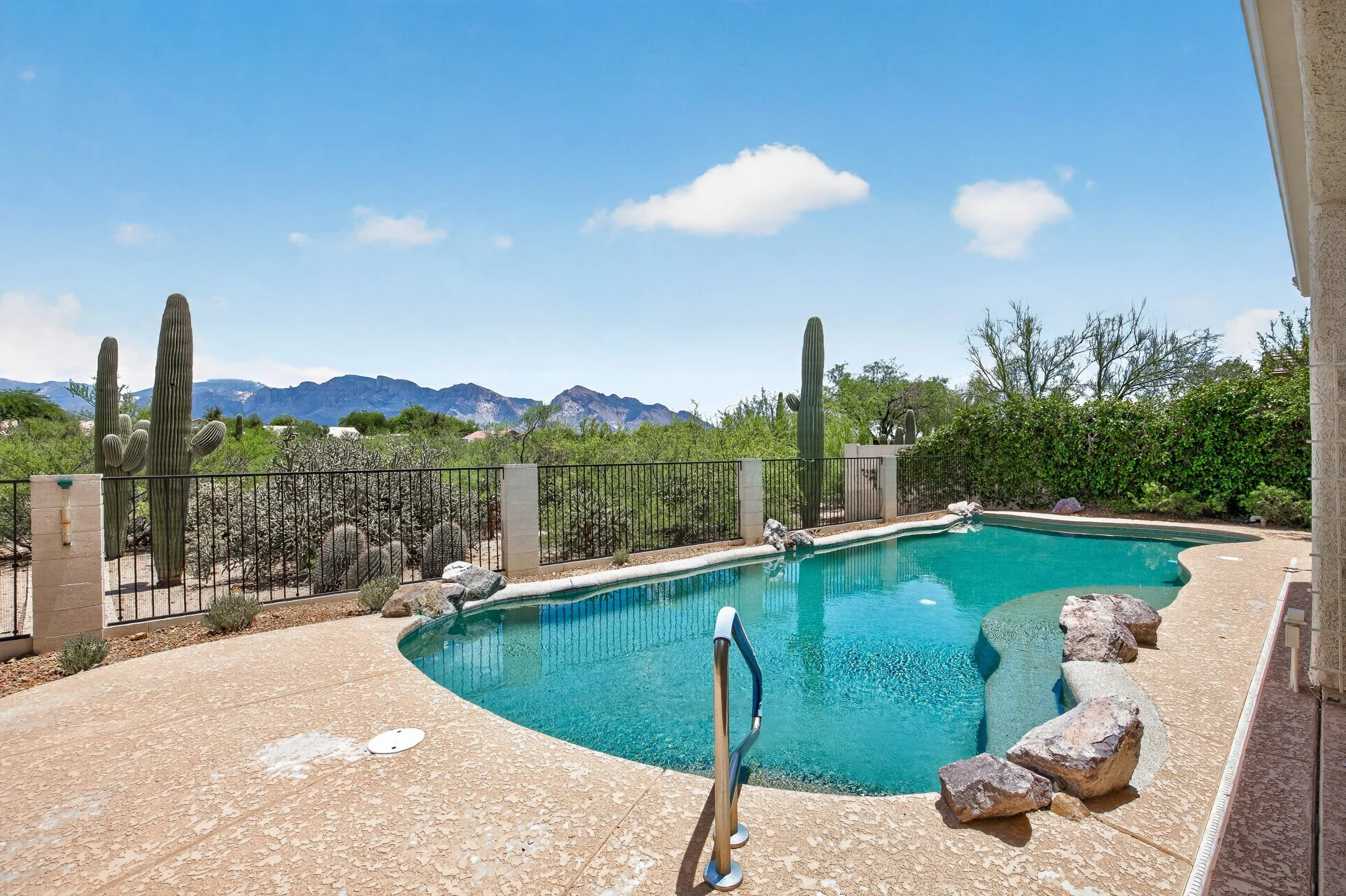 Pebble Tec pool at 11546 N Mountain Breeze Drive with saguaros and the Santa Catalina Mountains beyond the view fence