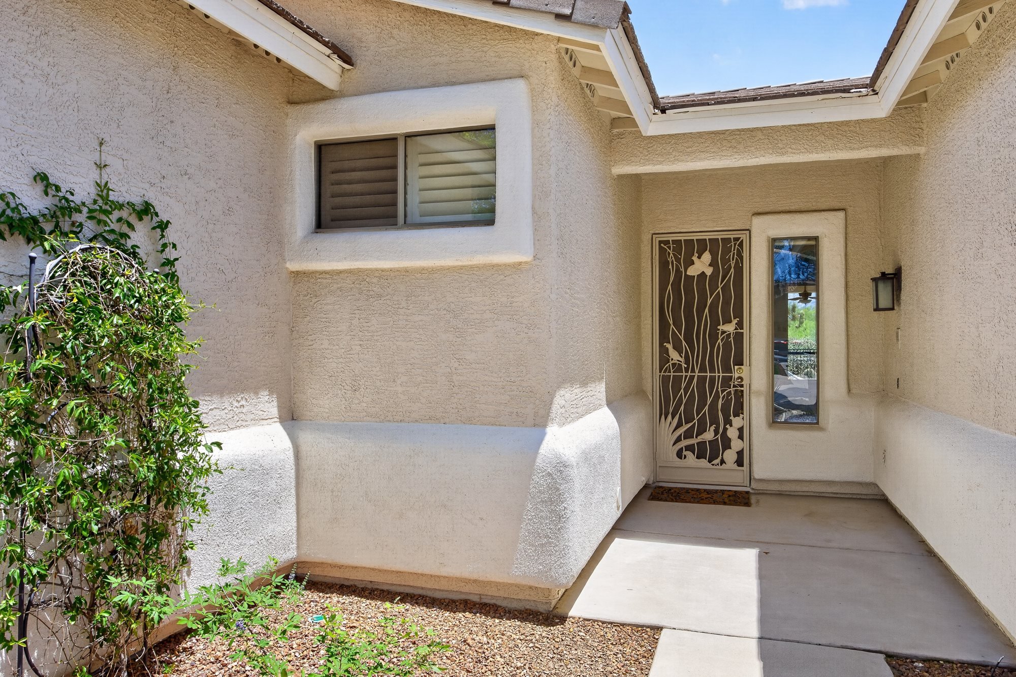 Shaded front entrance with wrought-iron security door and courtyard