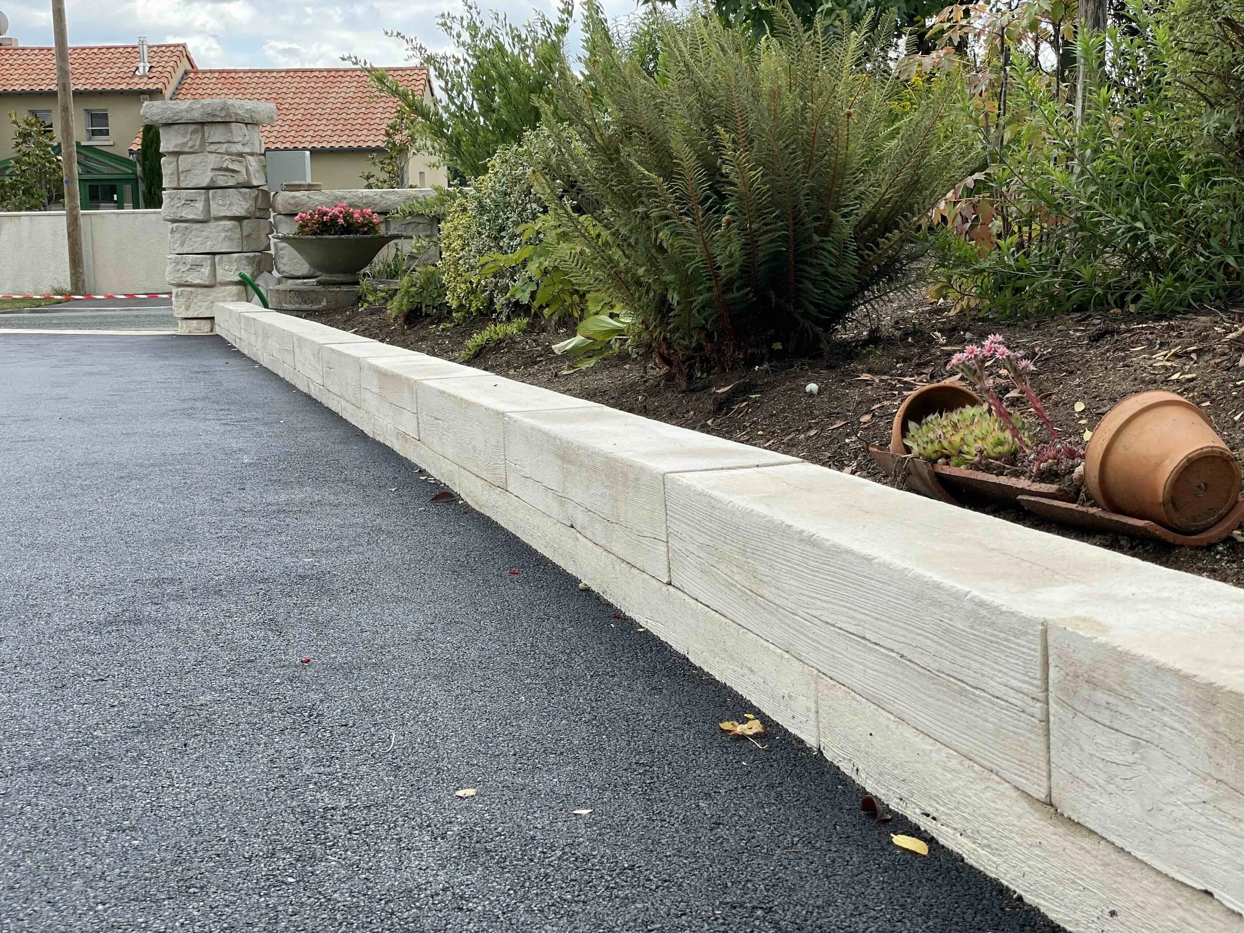 Terraced Heartwood retaining walls behind a residential pool, lit at night with landscape uplighting