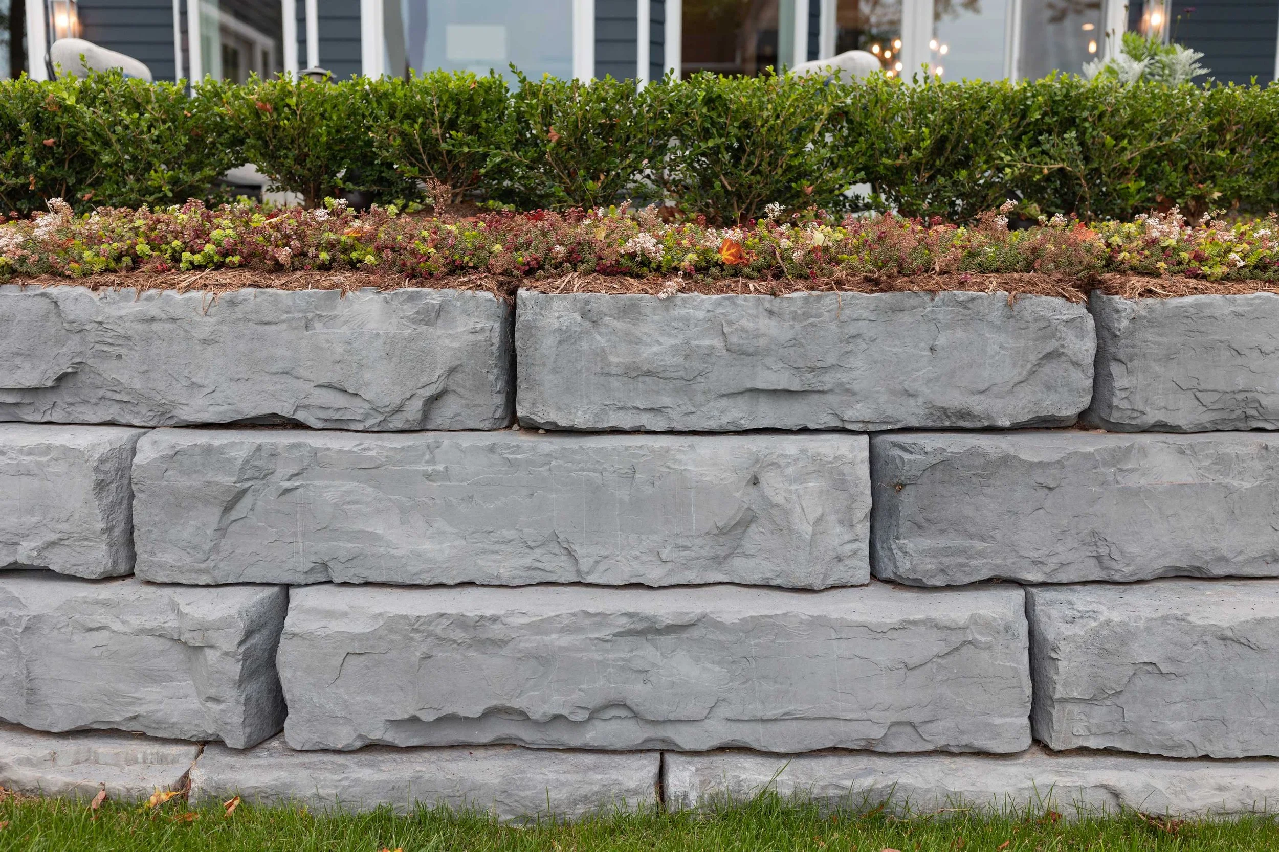 Grand Ledge retaining wall holding a residential grade change, with low plantings along the top course