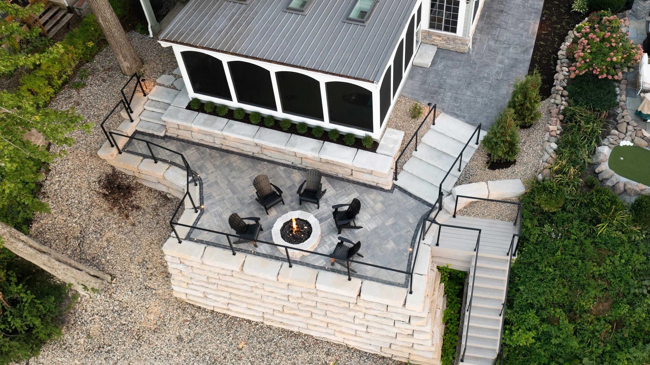 Aerial view of a Grand Ledge terraced outdoor living area with fire pit patio, screened porch, and paver steps