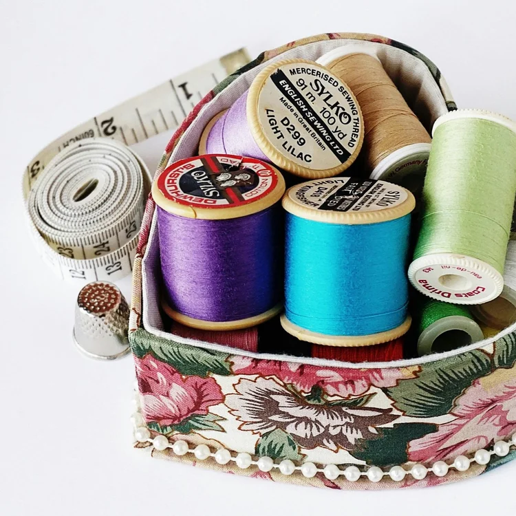 Nähkästchen mit Garnspulen und Maßband.