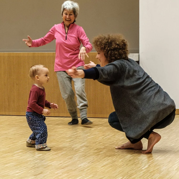Drei Menschen unterschiedlicher Generationen von Kleinkind zu Seniorin tanzen.