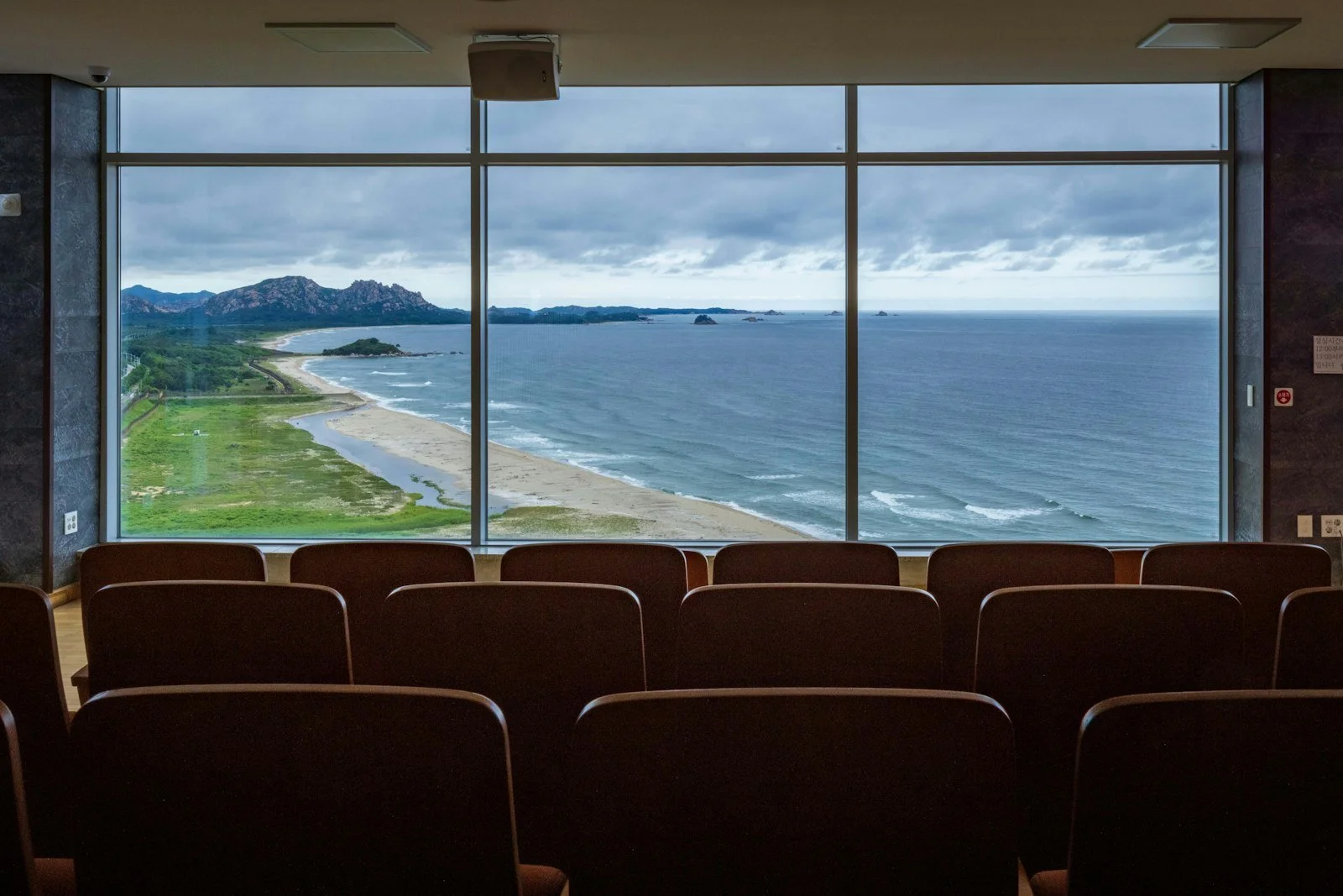 A meeting room with floor-to-ceiling windows overlooking the ocean and a beach