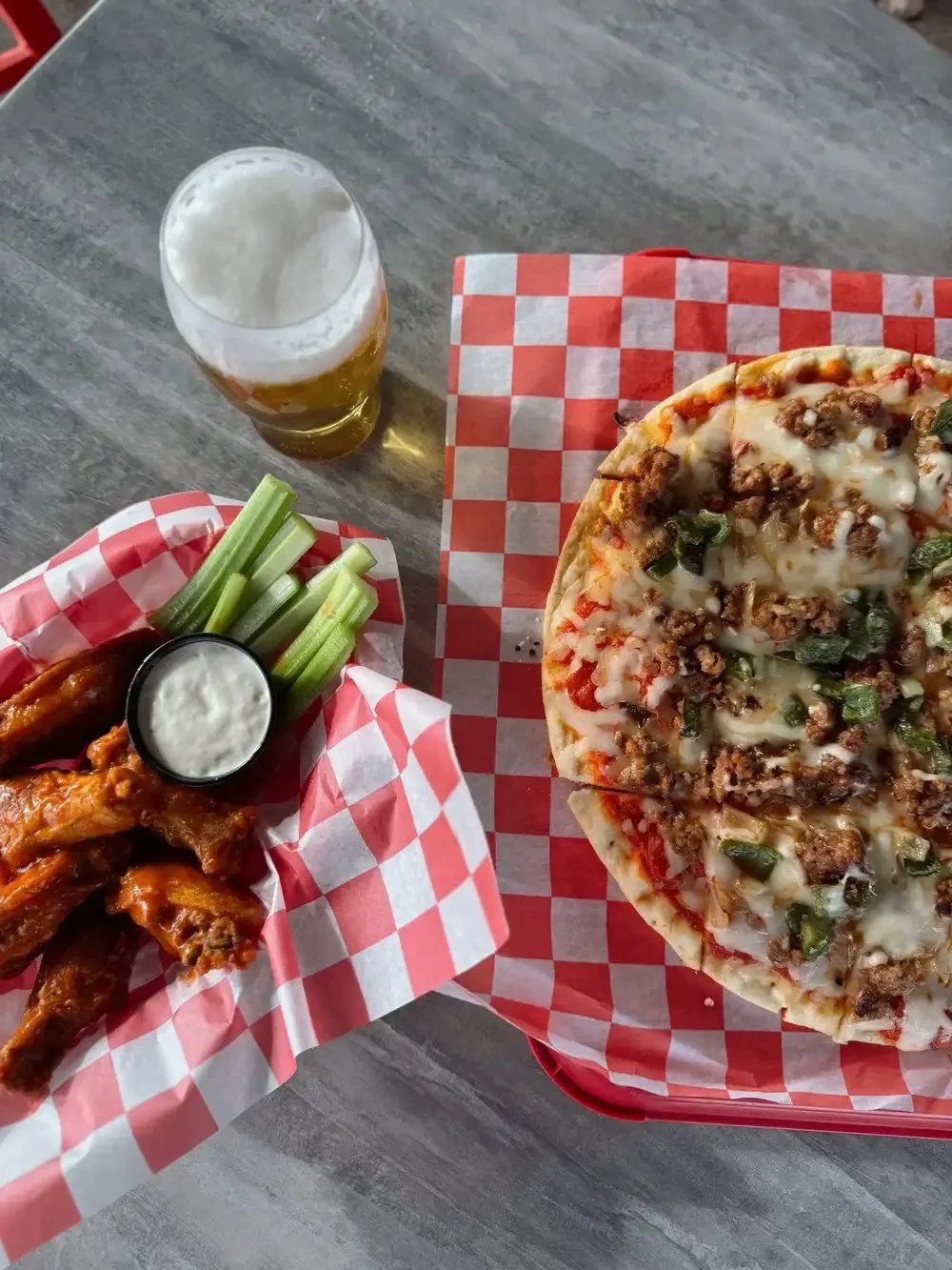 Pizza, chicken wings and beer arranged on a Chicago Beef Joint table