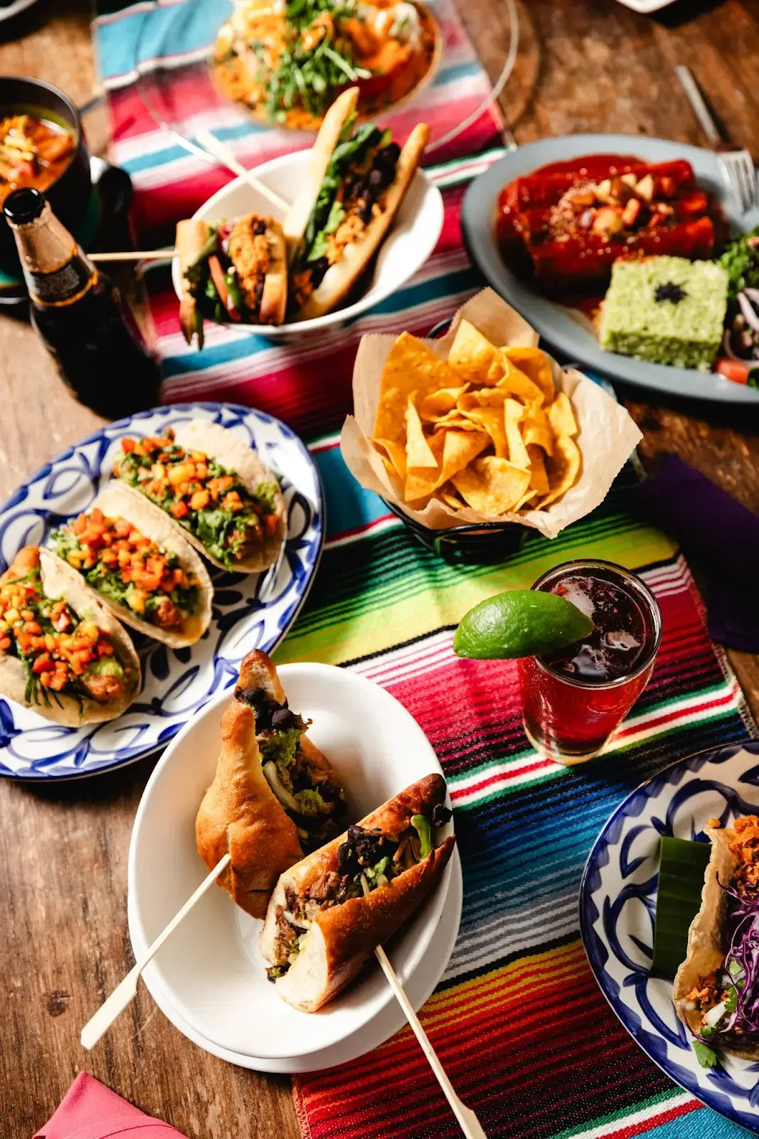 Tacos, tortas, chips and colorful MeXo dishes arranged on a striped table runner