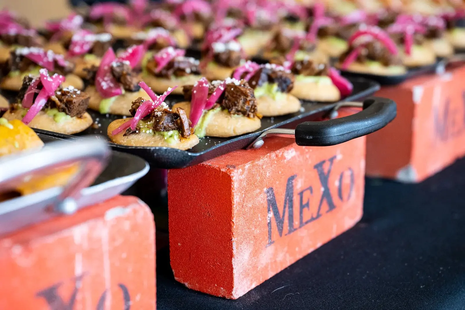 Rows of garnished hors d’oeuvres on MeXo-branded catering stands