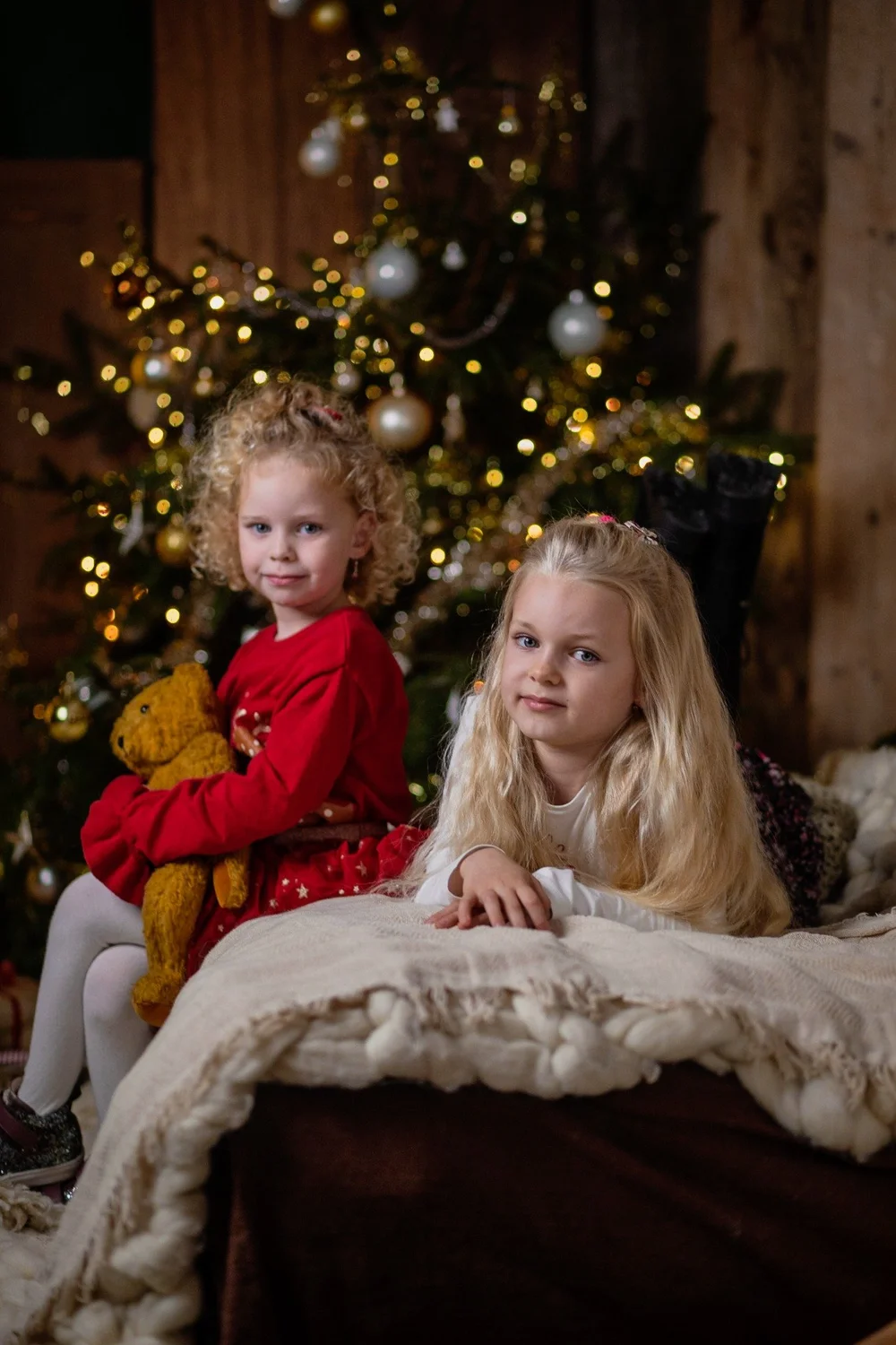 Zwei Kinder vor einem Weihnachtsbaum mit Lichterkette