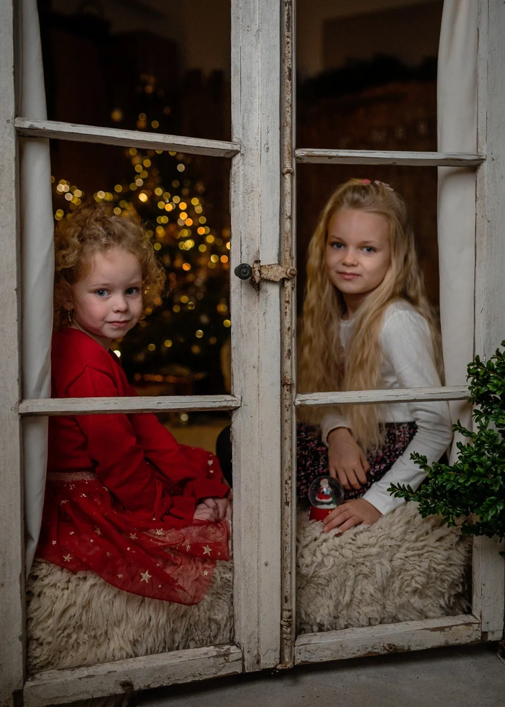 Zwei Kinder am Fenster in weihnachtlicher Kulisse