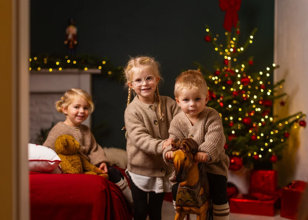 Drei Kinder vor einem Weihnachtsbaum