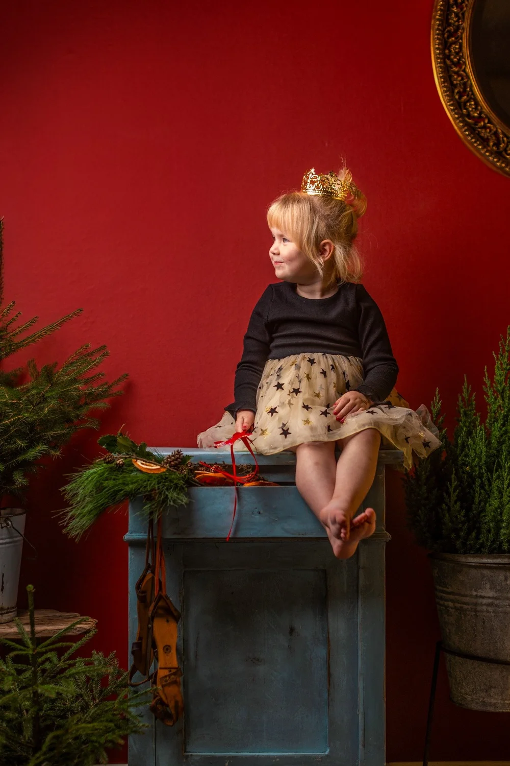 Kind mit Krone in roter Weihnachtskulisse