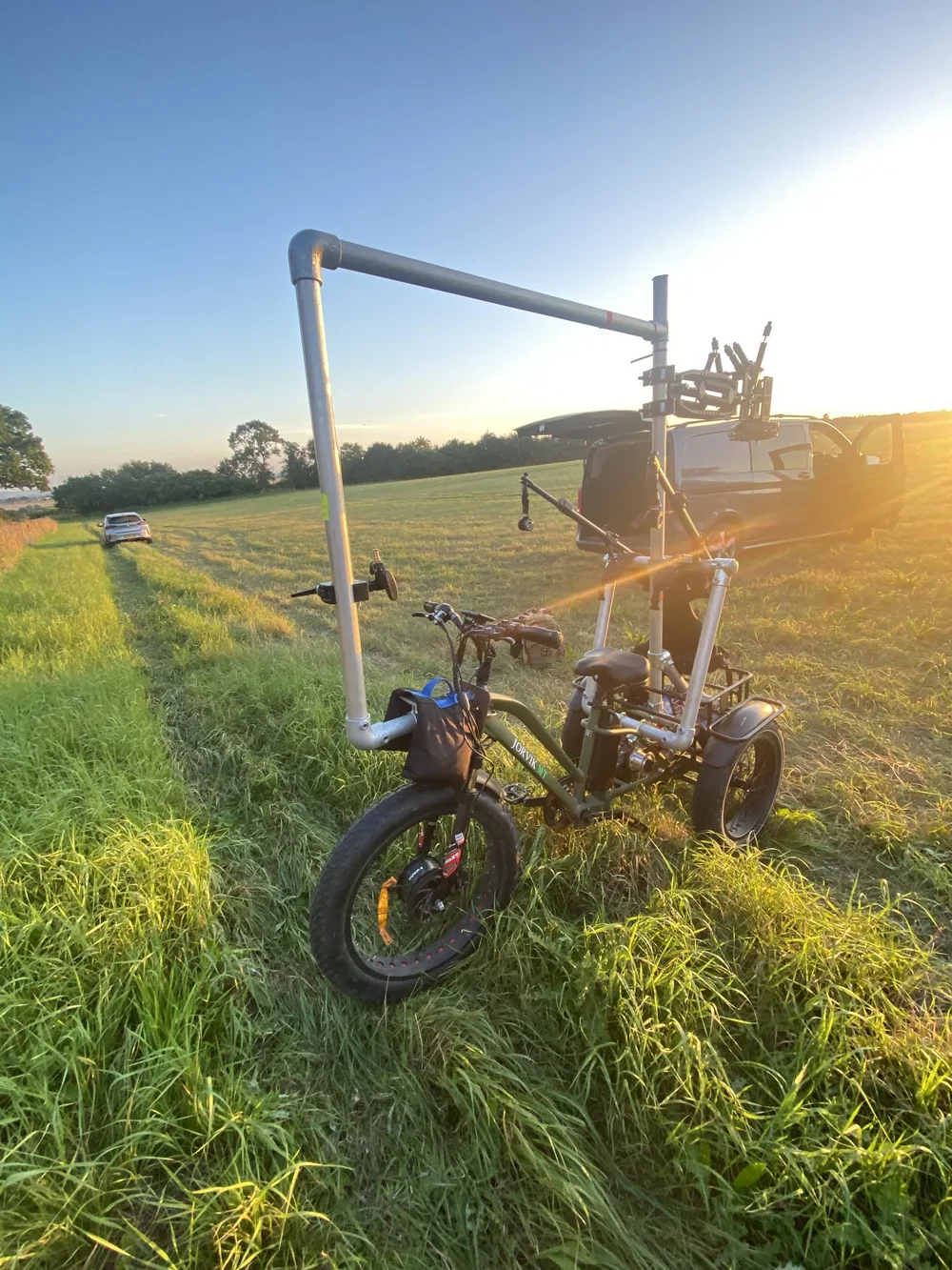 Electric camera trike in a field at sunset
