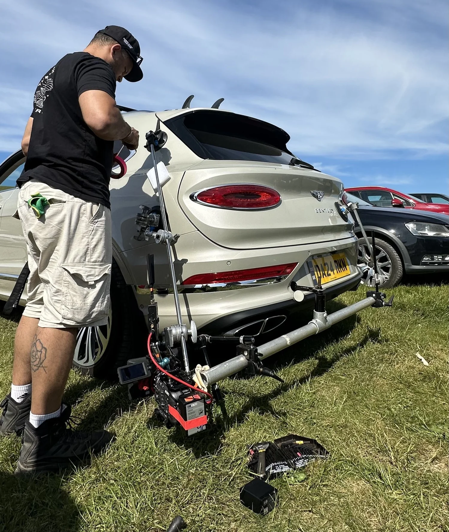 Technician rigging a tracking arm onto a car for a commercial shoot