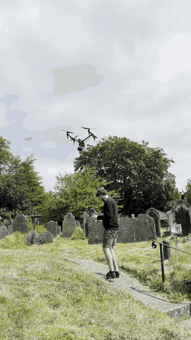 DJI Inspire 3 flying over a churchyard, with the pilot below