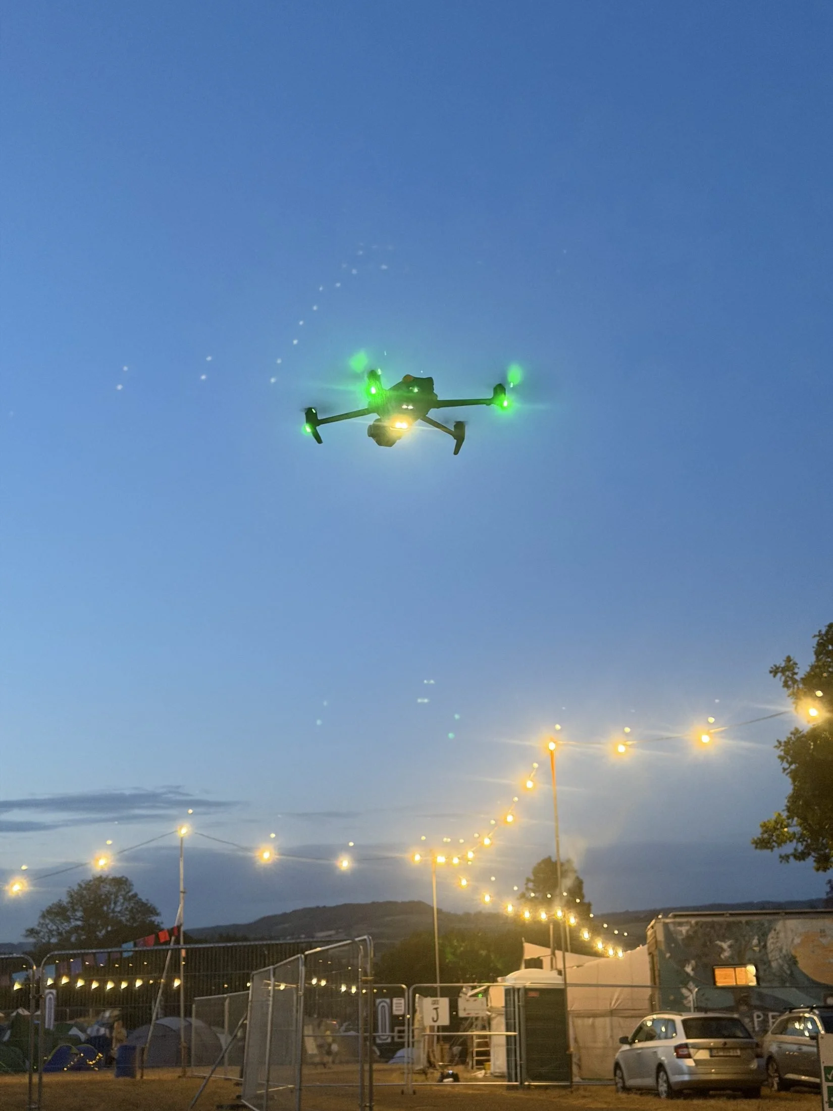DJI Mavic flying at dusk over an event with festoon lights