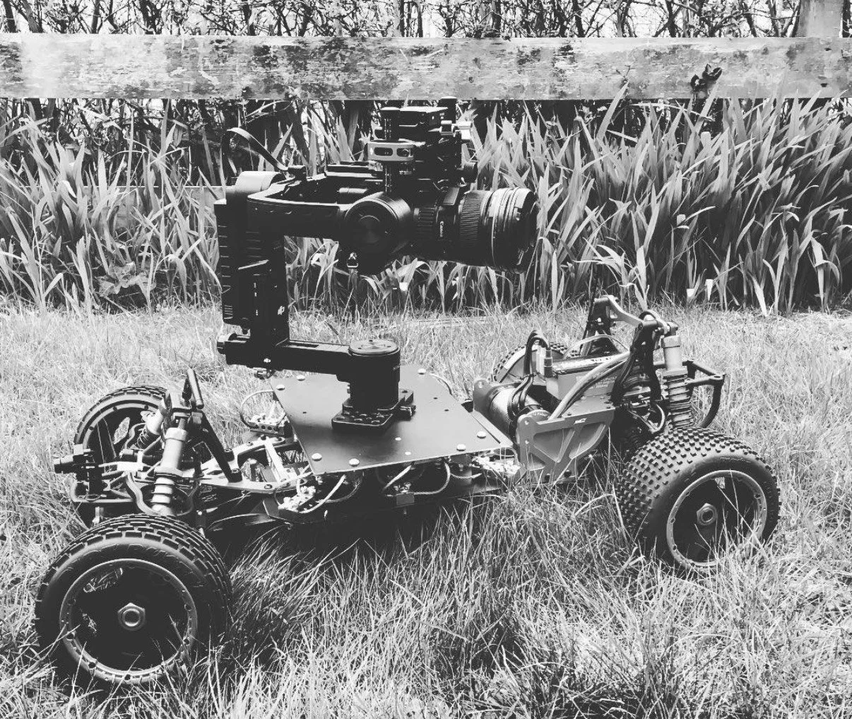 Scale 4x4 remote camera car carrying a gimbal and cinema camera in long grass