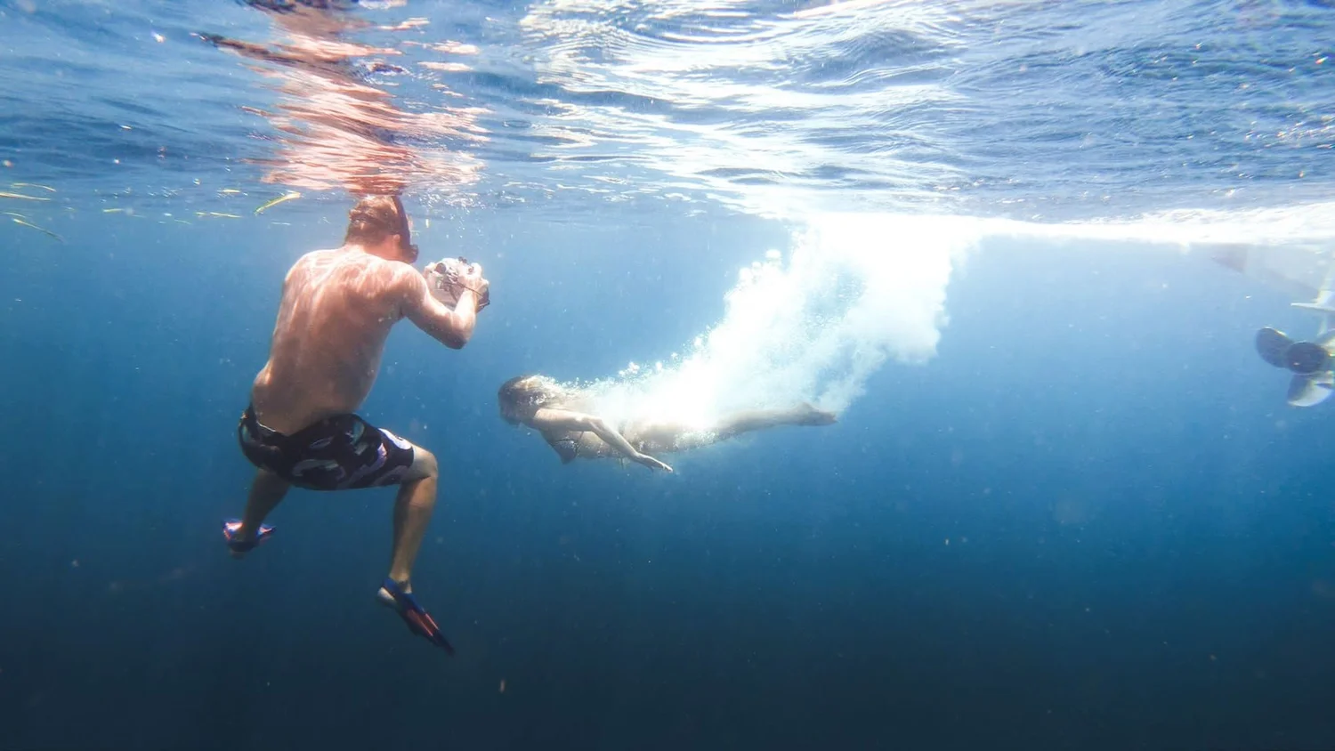 Underwater camera operator filming a diver from below the surface