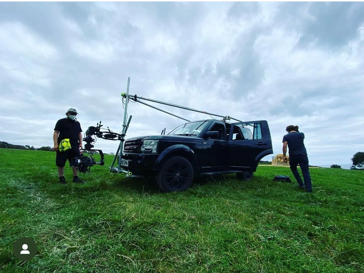 Camera car with a crane arm and gimbal rigged for a tracking shot in a field