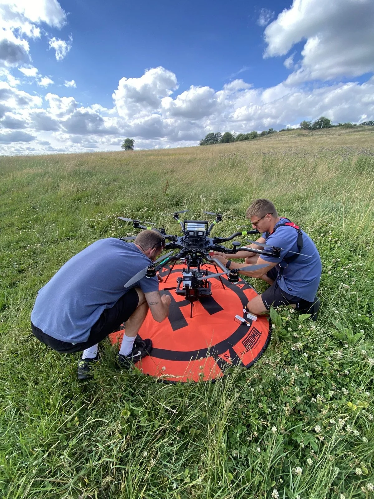 Two crew prepping the Alta 8 heavy lift drone on its landing pad in a field