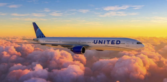 United Airlines aircraft flying above the clouds at sunset