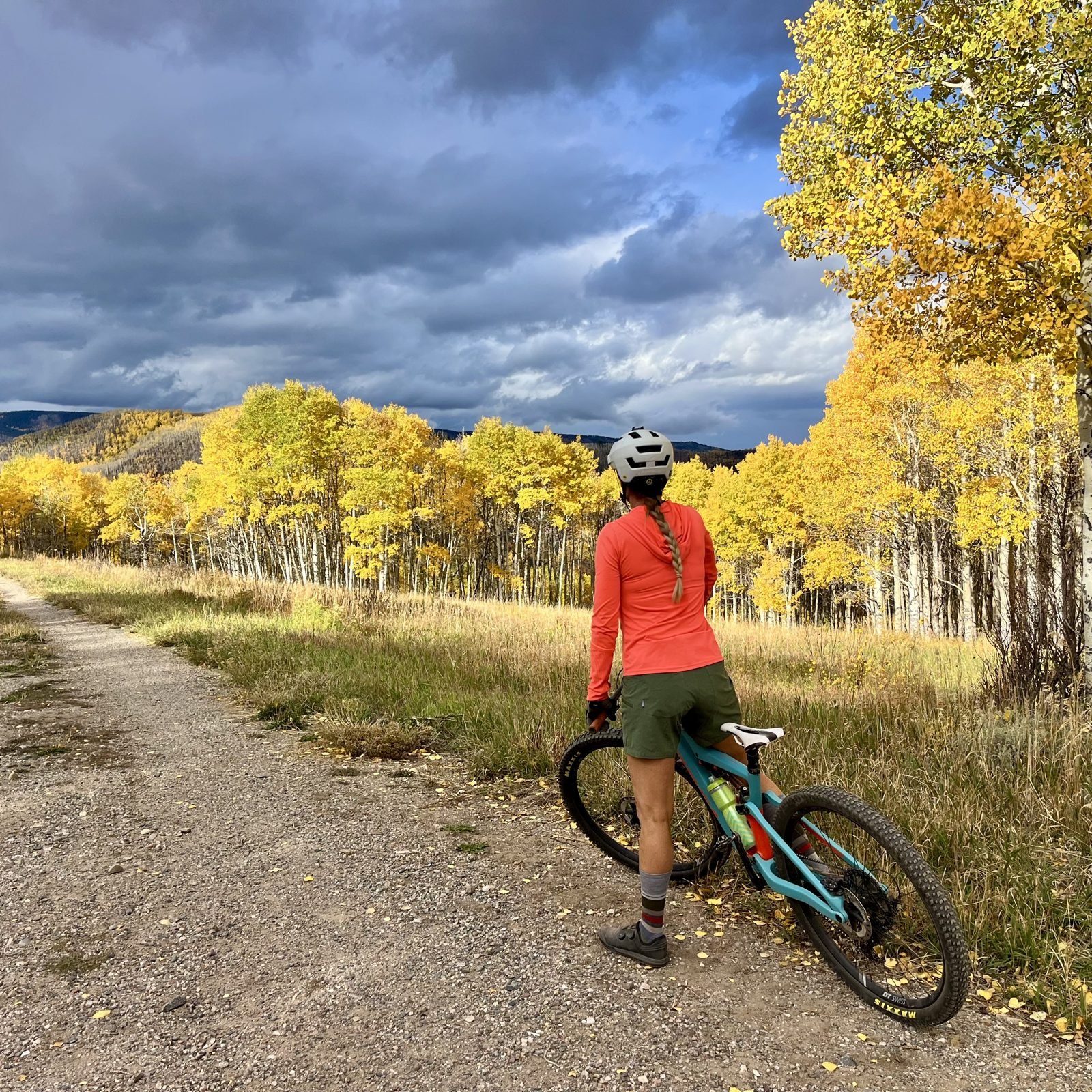 Rider pausing on a gravel trail through golden aspen trees