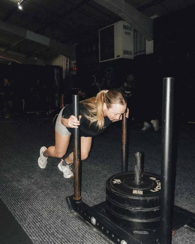 Member driving a weighted sled in a HYROX session