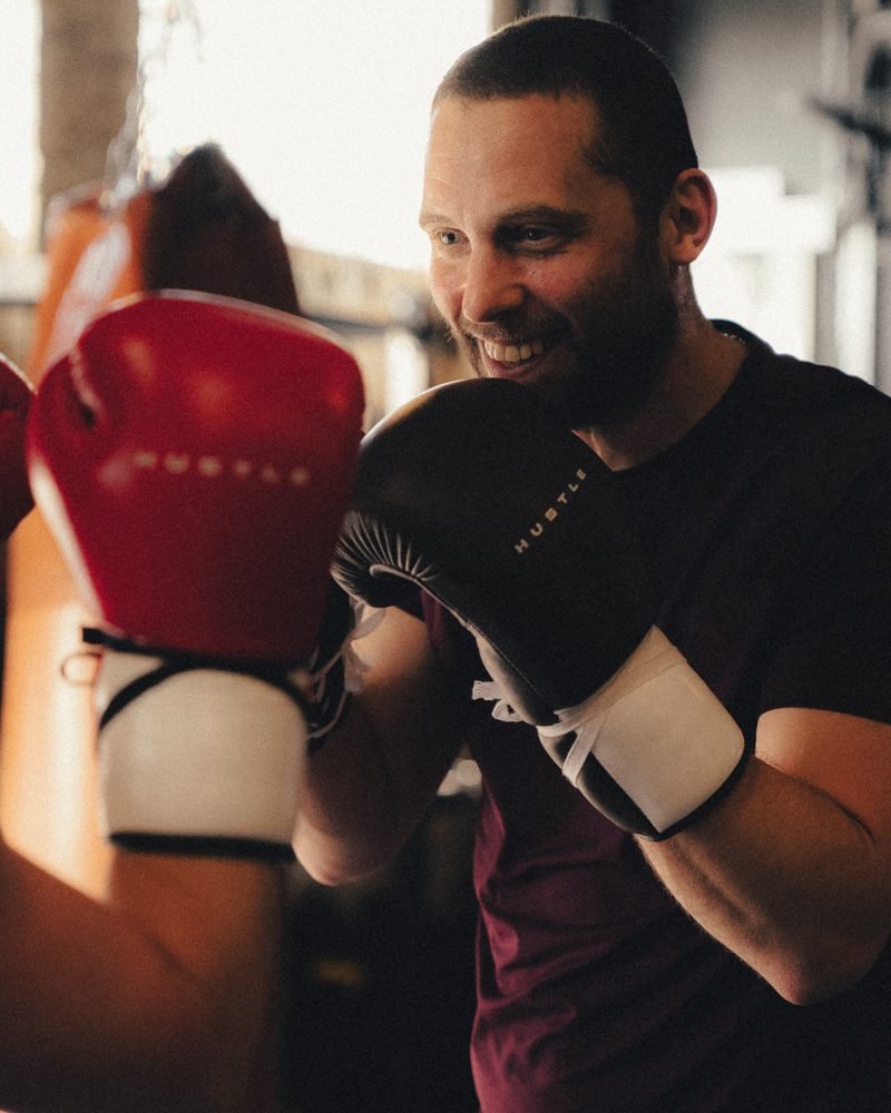 Smiling member on the pads in Hustle boxing gloves