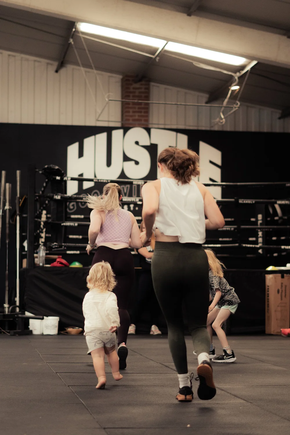 Mums and toddlers running together in a Strong Mums Club session at Hustle