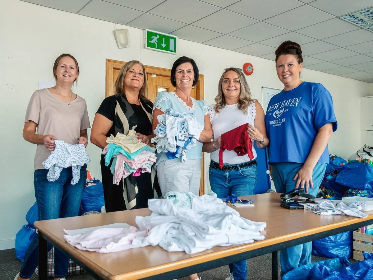 A group of volunteers sorting baby clothes together at a table