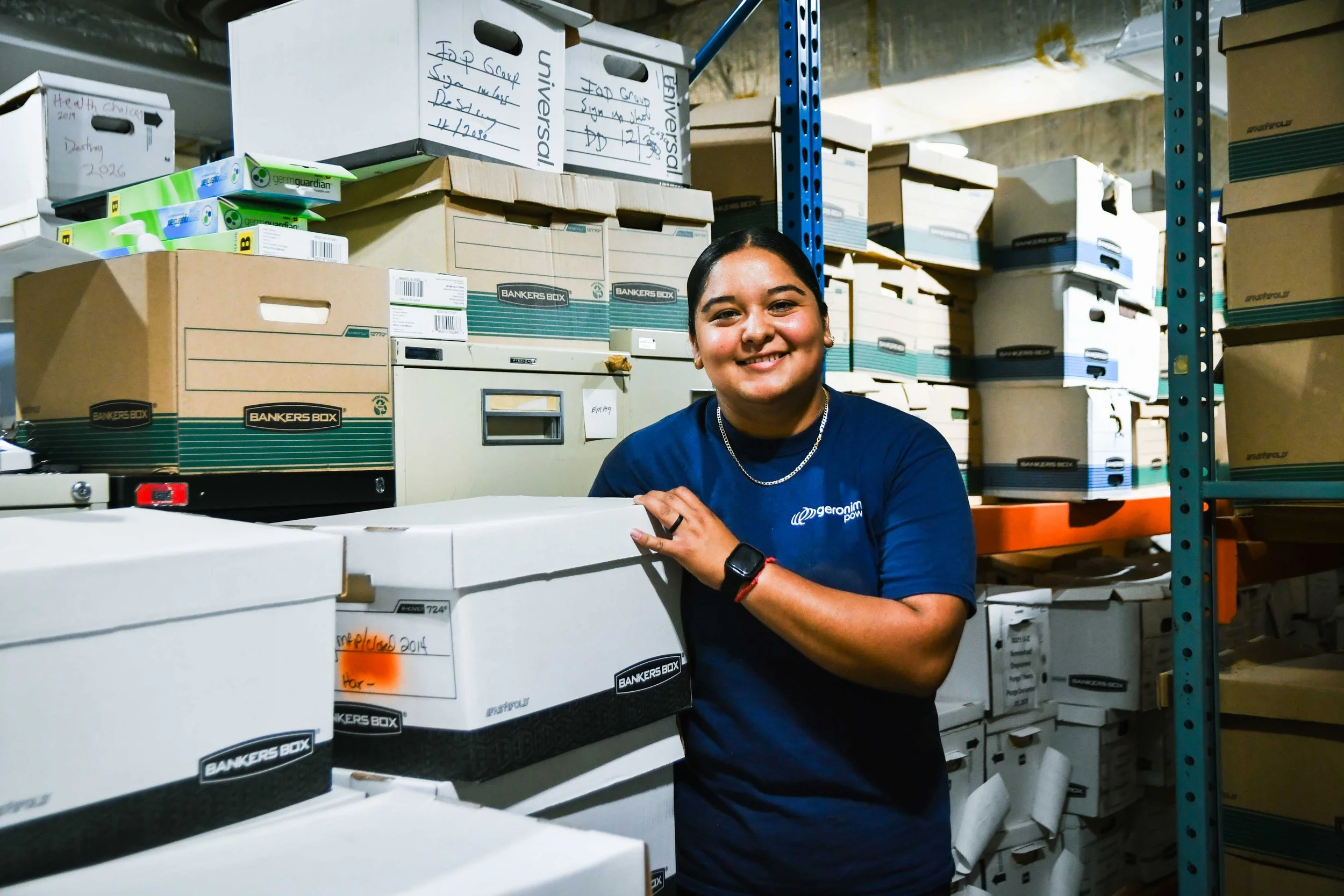 Geronimo Powers volunteer posing with archive boxes from the Avivo basement