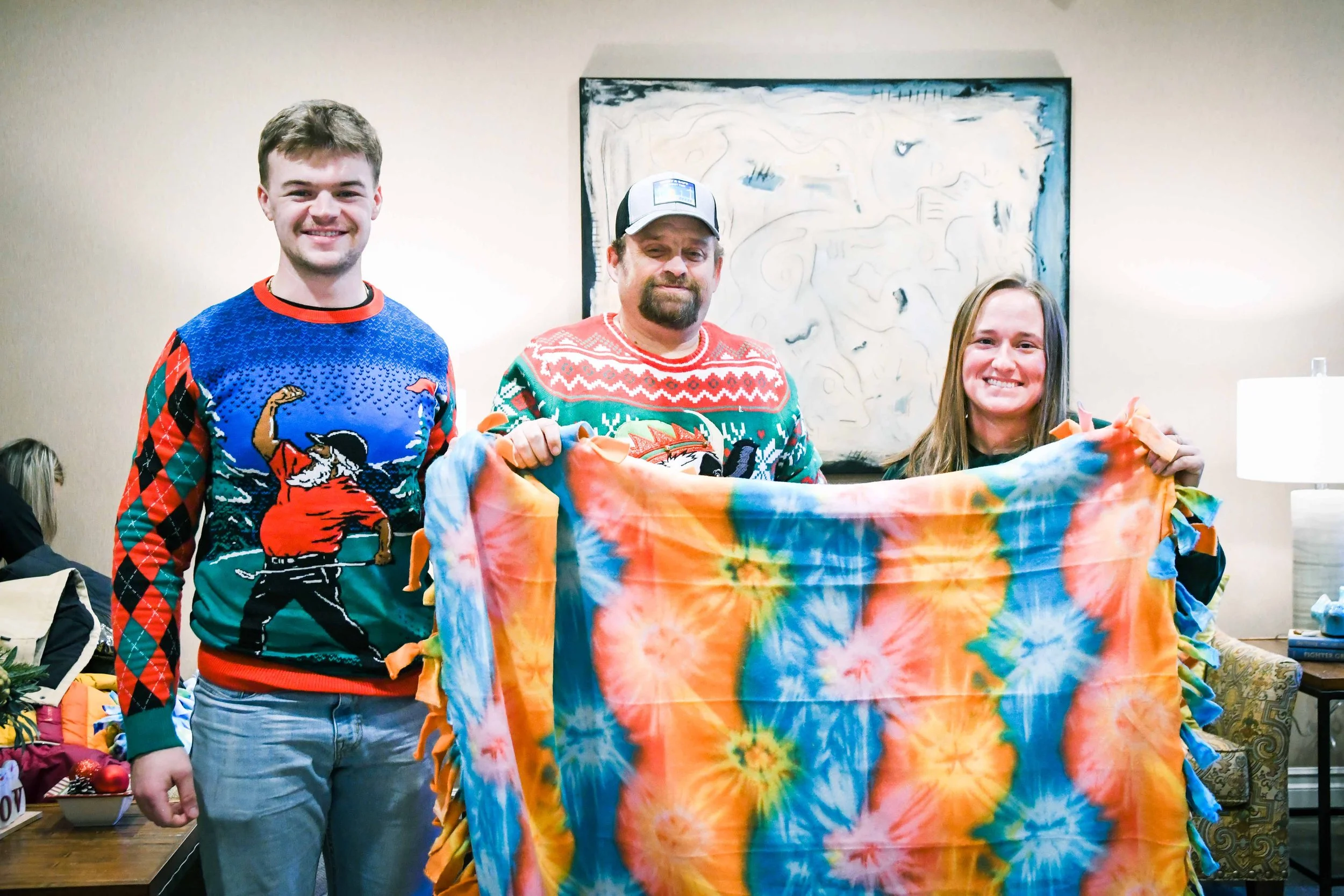 Geronimo Power volunteers posing in front of a no-tie fleece blanket they made during their holiday engagements