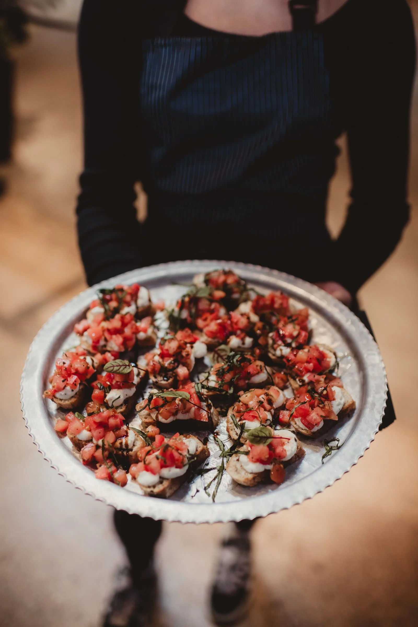 A server presenting tomato crostini during cocktail hour