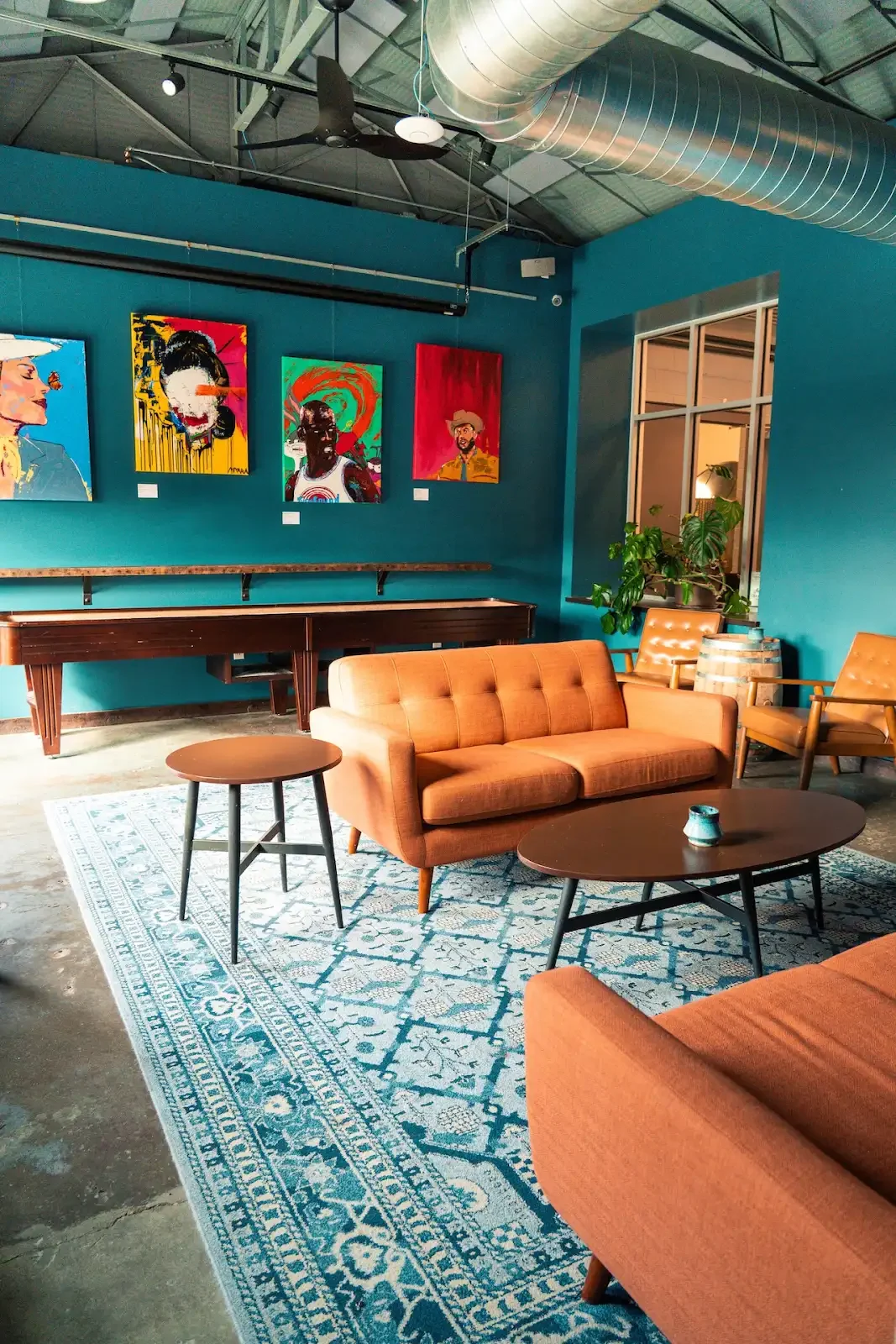 State Line’s Gallery Room, with teal walls, artwork and warm leather seating
