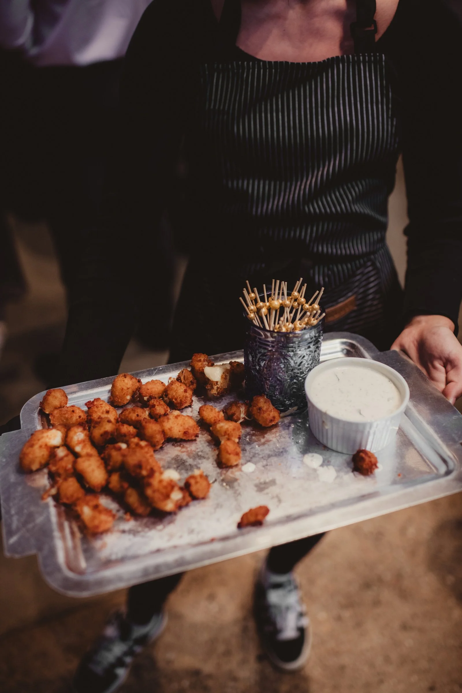 A server presenting warm small bites with dipping sauce
