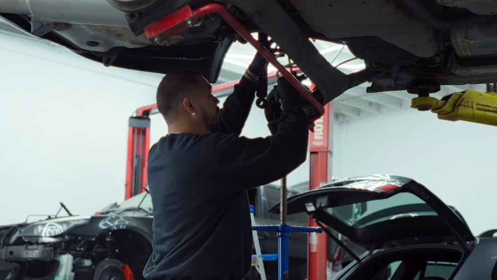 A second mechanic working beneath a raised car