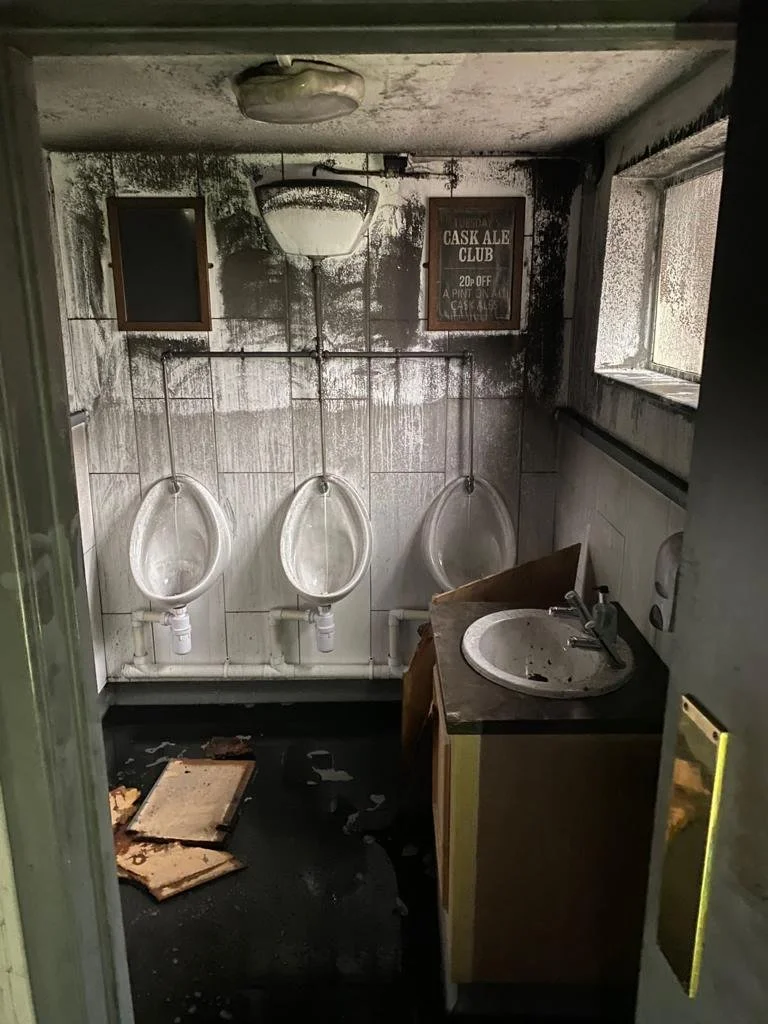 Fire- and smoke-damaged pub bathroom before professional cleaning