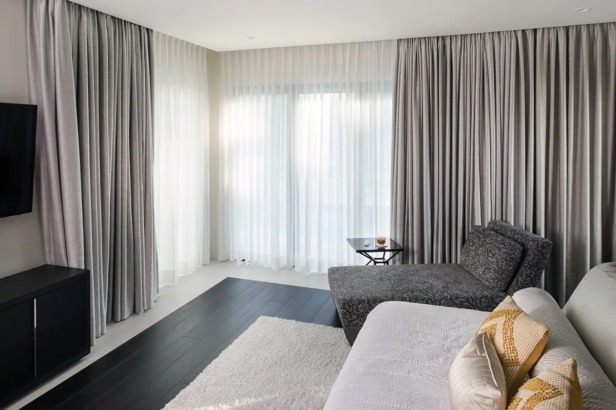 Lutron motorized drapery with dual track sheer and main panels in contemporary lounge with floor to ceiling windows