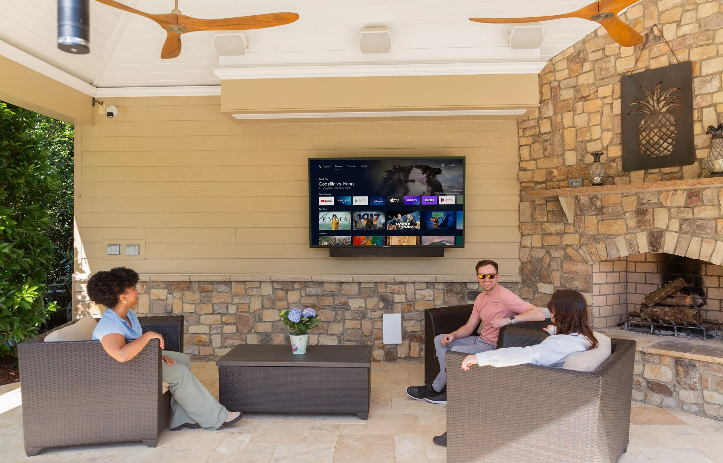 People watching SunBrite outdoor TV showing Android TV streaming interface on covered patio installation by VIP Smart Homes Seattle