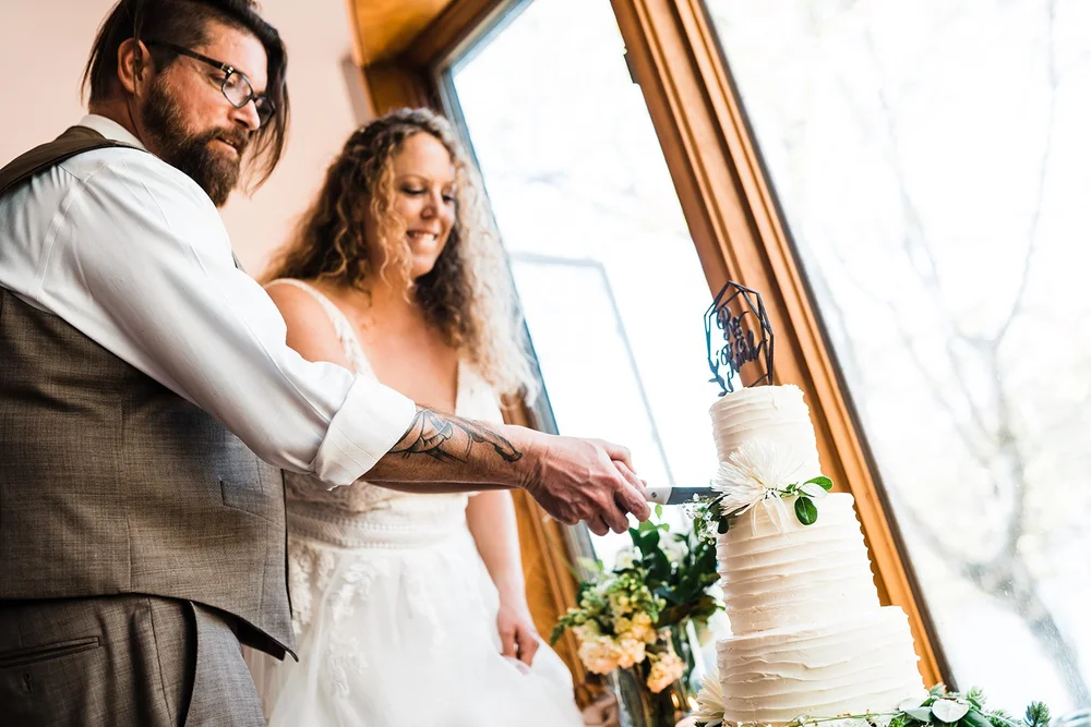 Kimb and Roland cutting their wedding cake together back at the cabin