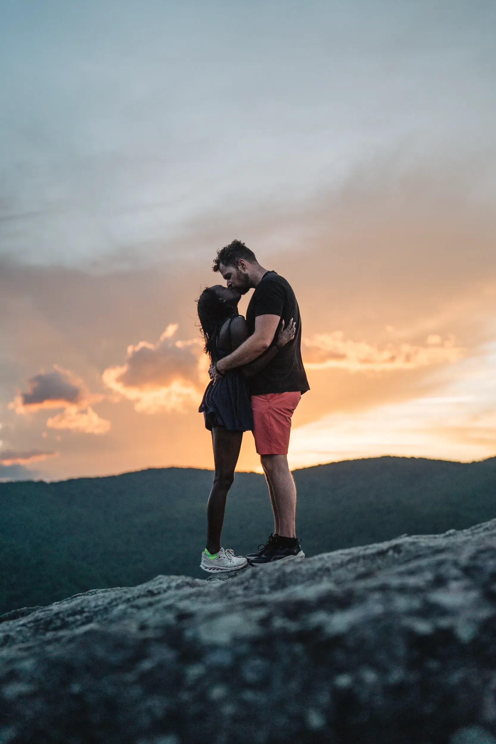 Newly engaged couple holding each other at a mountain overlook near sunset