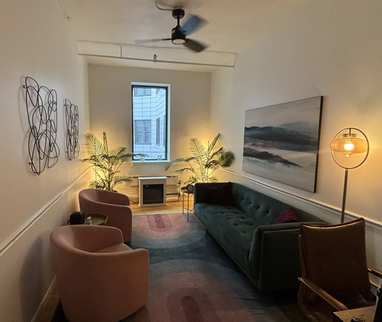 A warm therapy room at BIPS Union Square with pink armchairs and a green sofa