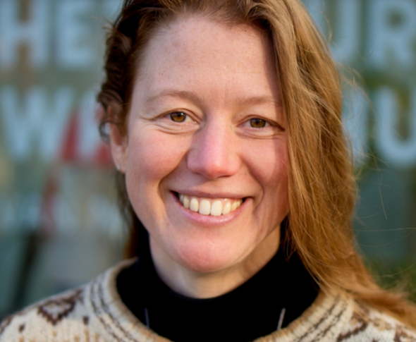 Portretfoto van een lachende vrouw met lang bruin haar. 