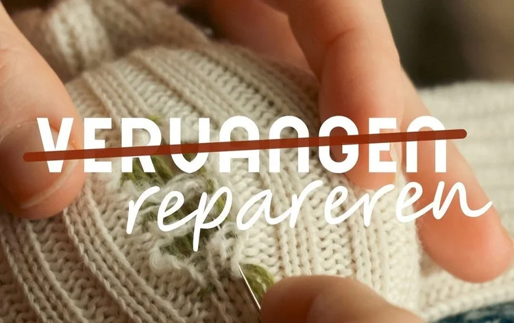 Close-up van een hand die naald vasthoudt om een gebreide witte trui met een gat te repareren