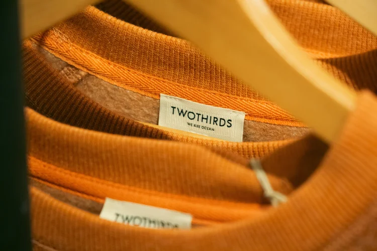 Close-up van het label in twee oranje T-shirts aan een houten hanger