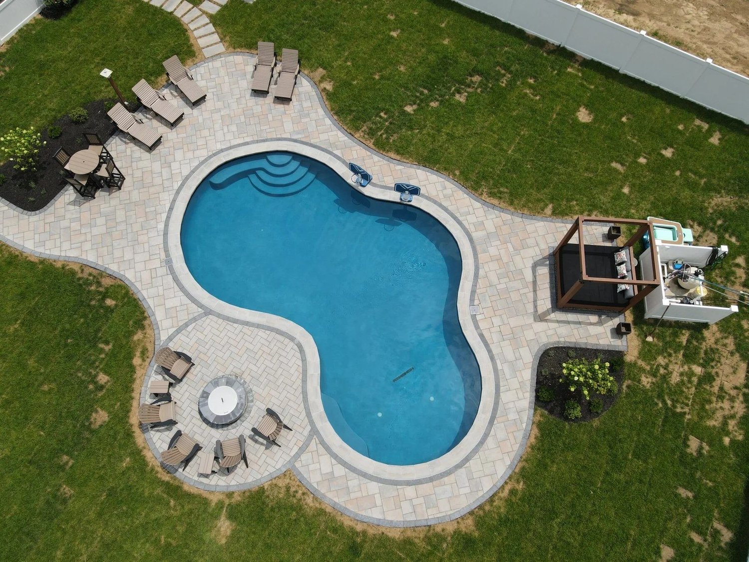 Overhead view of the renovated Gambrills pool with blue water, curved paver terrace and circular firepit seating area
