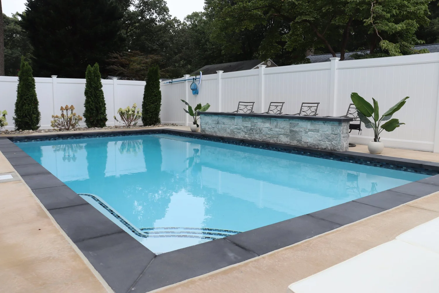 Completed rectangular swimming pool in Annapolis with a raised stone wall and surrounding concrete terrace